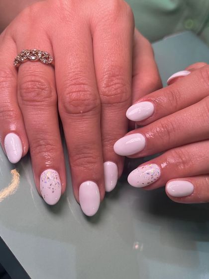 A simple and sweet manicure with a milky white base and a touch of scattered glitter on the accent nails.