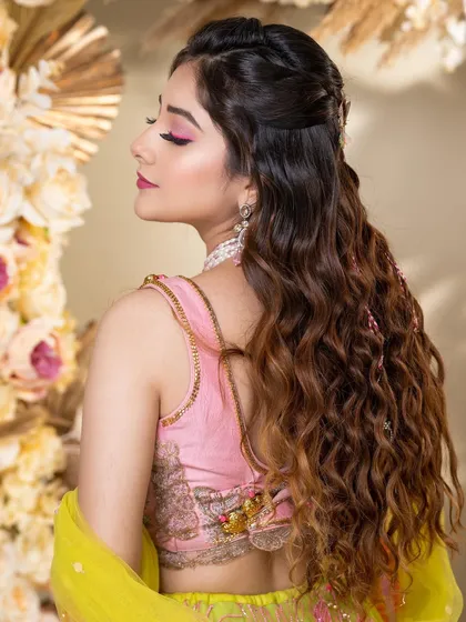 A side view highlighting the beautiful beachy waves and the pop of pink on the eyes. This look is all about modern, fun, and festive glamour.