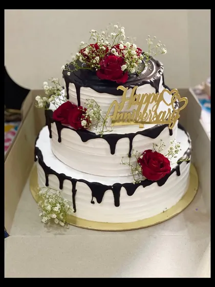 This five-kilogram, three-tier chocolate truffle cake was the centerpiece for a beautiful anniversary celebration. I love creating these grand cakes, decorating them with fresh roses and baby's breath for an elegant touch.