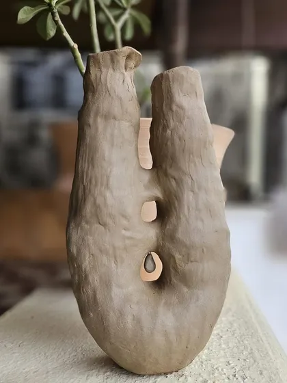 An abstract, hand-built vase with organic cutouts. This piece explores negative space and texture, creating a form that feels both strong and delicate.