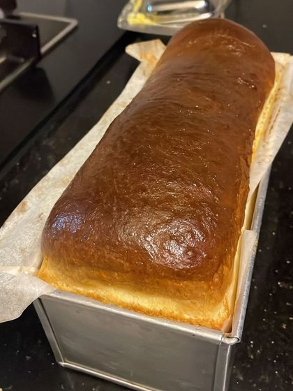 A freshly baked loaf of brioche, golden brown and ready to be sliced for French toast or served with butter.