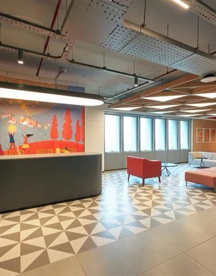 The reception and pantry area from our 4.5 lac sq ft project in Hyderabad. The space is defined by geometric floor tiles and a large, colorful mural, immediately setting a vibrant tone for the office.