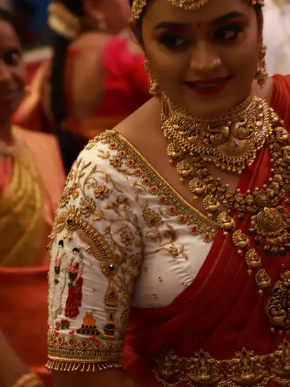 Seeing a bride's happiness is the best part of my work. Here is a client looking radiant on her wedding day in a custom white and red blouse, featuring intricate bride and groom figures embroidered on the sleeves.