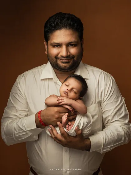 A proud father holds his sleeping miracle. This portrait is about the strength and tenderness of a father's love, a bond that is instant and everlasting.