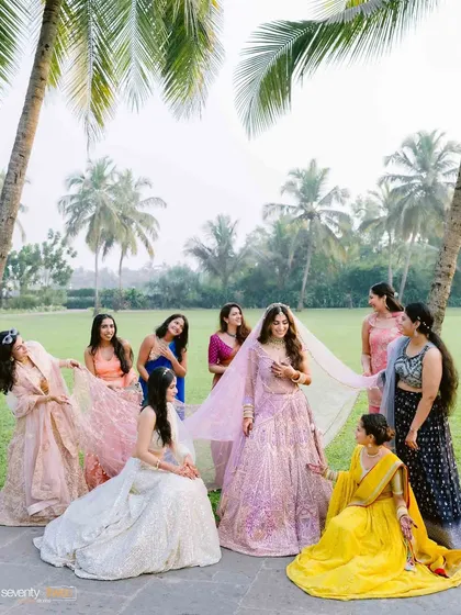 The bride sharing a moment with her bridesmaids on the lush lawns of the Goa resort, with palm trees framing the happy scene.