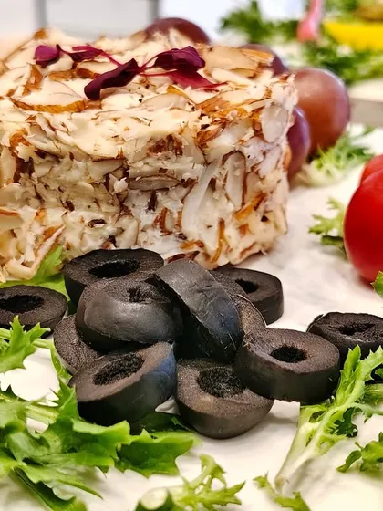 Say cheese to culinary elegance! This almond-crusted cheese round is the star of the board, surrounded by crisp greens, juicy tomatoes, and black olives.