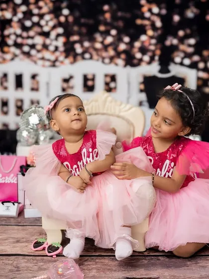 A sweet, candid moment between two sisters in their matching Barbie outfits.