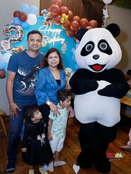 A happy family posing with our friendly panda mascot during a teddy bear themed birthday party.