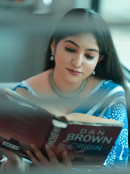 A beautiful portrait of the bride-to-be, captured through the train window. Her reading a book adds a lovely storytelling element to the pre-wedding shoot, suggesting a journey and a shared story.