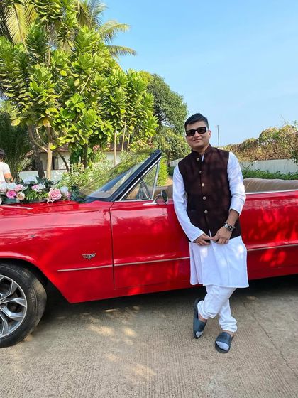 Posing with the vintage car for the groom's entry. Every detail of the Baraat is planned for maximum impact.