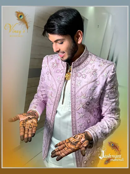 A side profile of the groom admiring his intricate henna design before the big day.