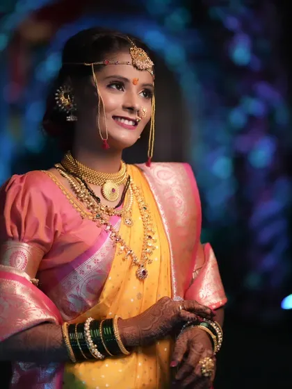 The quintessential Maharashtrian bride. This close-up highlights the traditional crescent bindi, the glow of HD makeup, and the intricate details of the nath and gold jewelry that are central to this beautiful look.