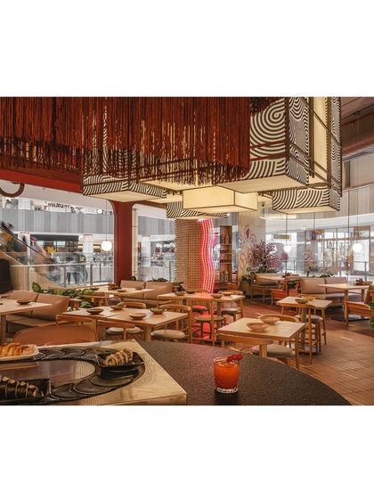 An overhead view showing the relationship between the sushi bar, dining tables, and the larger mall environment. The restaurant's design successfully carves out a unique and cohesive space.