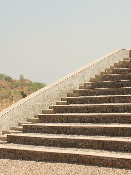 A side view of the amphitheater steps, showing their clean, geometric lines against the arid landscape. The design is both monumental and respectful of its natural setting.