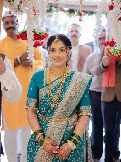 The bride's grand entrance. Dressed in a beautiful teal saree and adorned with gold jewelry, she looks every bit the traditional Maharashtrian queen.