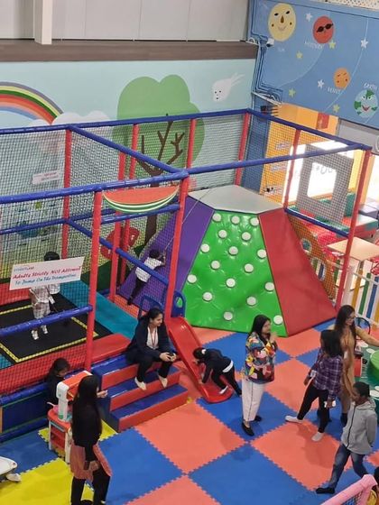 This wide shot shows the heart of our play area, with its climbing structures, trampoline, and soft play zones. It's a safe, netted environment where kids can explore freely while parents watch from nearby.