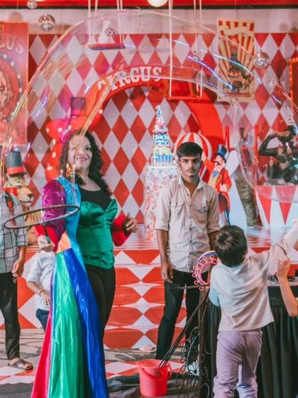 A performer creates giant bubbles, delighting children at Avyaan's circus party. Interactive entertainment is essential for keeping young guests engaged and making the event fun for everyone.