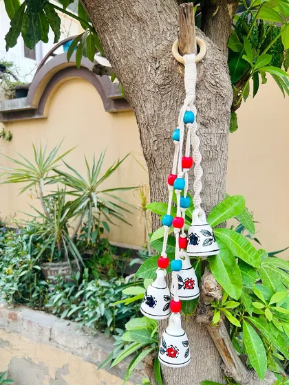 Our 'Symphony Chimes' in the 'Gulmohar' variant, hanging outdoors. The red and blue beads add a pop of color, making it a perfect piece for Diwali decor or as a thoughtful gift.