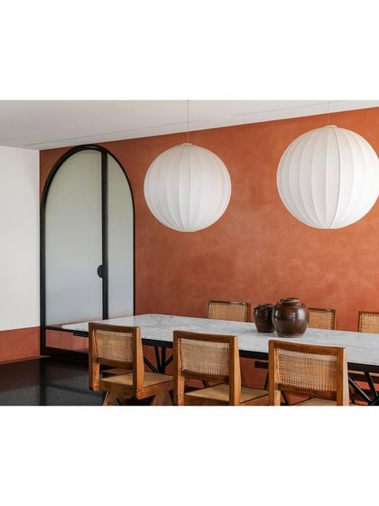 The dining area, featuring the long marble table I designed. The spherical pendant lights above cast a soft glow, highlighting the beauty of the stone and the craftsmanship of the chairs.