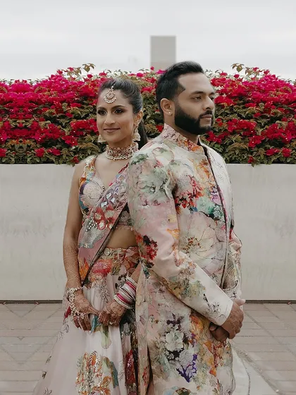 A back-to-back pose showing the beautiful coordination between the bride's and groom's floral outfits. Their styles complement each other without being identical.