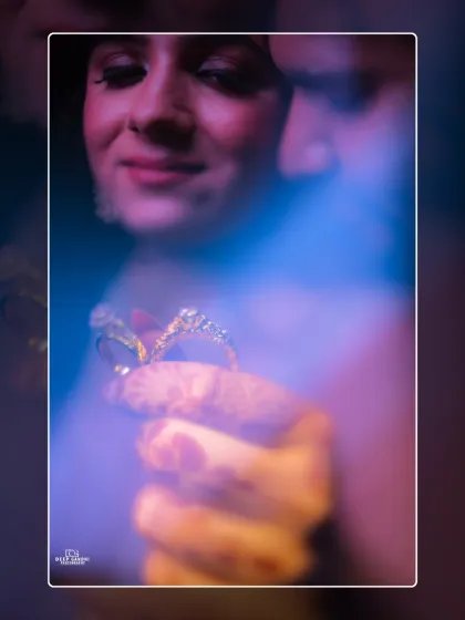 An artistic shot of the engagement rings, blurred with a creative blue light flare. This abstract photo focuses on the symbol of their commitment.