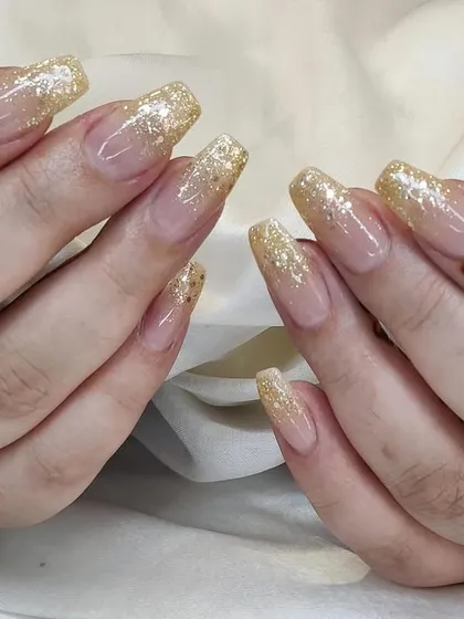 A glamorous set of square-tipped nails with a chunky gold glitter fade, perfect for weddings and festive occasions.