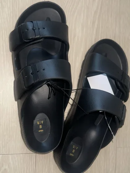 A pair of black Birken-inspired sandals. This classic two-strap style is comfortable, durable, and perfect for everyday wear.
