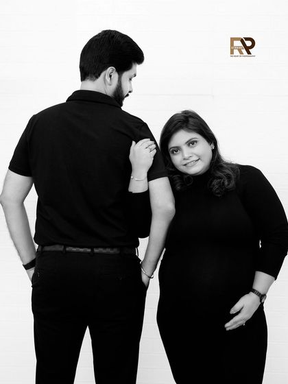 A sweet and simple black and white portrait. The mom-to-be rests her head on her partner's shoulder, creating an image that is both intimate and timeless.