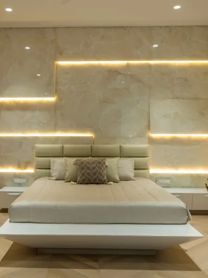 This bedroom uses layered lighting against a stone-paneled wall to create a warm and inviting ambiance. The floating bed design adds to the modern, uncluttered feel of the space.