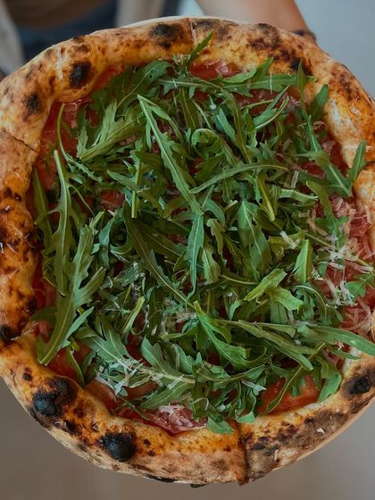 Holding our Prosciutto di Parma e Rucola pizza. It's a work of art.
