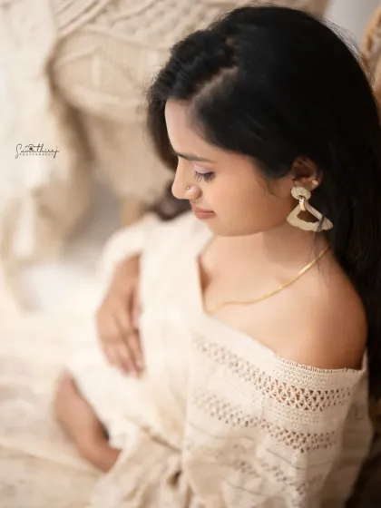 A serene and thoughtful portrait of a mother-to-be in a boho-chic setting. The soft focus and warm tones create a dreamy and intimate feel.