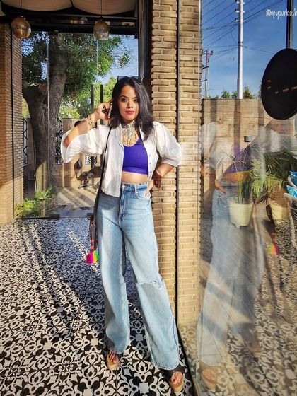 A trendy and casual look featuring wide-leg jeans and a purple crop top, layered with a white shirt. This is how you play with proportions and colors for a modern street style vibe.