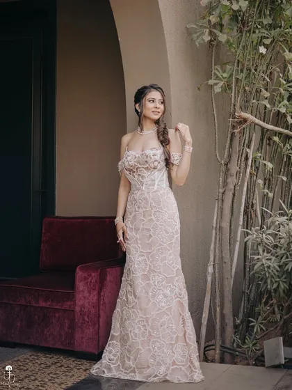 A full-length portrait of the Carnival look. The soft makeup and elegant hairstyle work in perfect harmony with the stunning off-white lace dress.