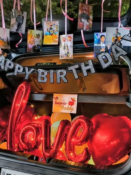 Combining love and birthdays in one surprise. This car dikki decoration features a "Happy Birthday" banner, hanging personal photos, and large red foil balloons spelling out "love" for a heartfelt and personalized message.
