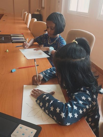 Two students work side-by-side, drawing lotuses during a guided session. Our classes are designed to be both educational and a great social activity.