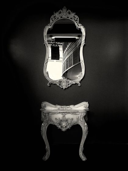 A detail shot from the Jollygunj project, focusing on the ornate, vintage-style mirror and console table. The black and white photography emphasizes the forms and the dramatic, high-contrast design.