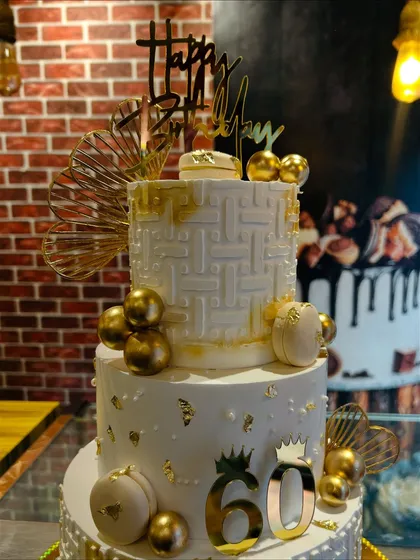 A detailed shot of the top tiers of the 60th birthday cake, highlighting the intricate texture and gold leaf accents.