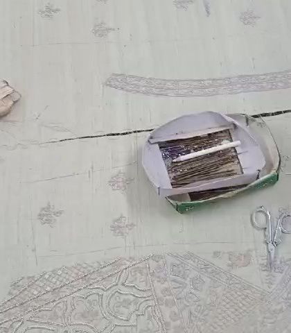 The beginning of a masterpiece. This image shows the tools of the trade, with thread, scissors, and fabric laid out as our artisans begin the intricate embroidery process.