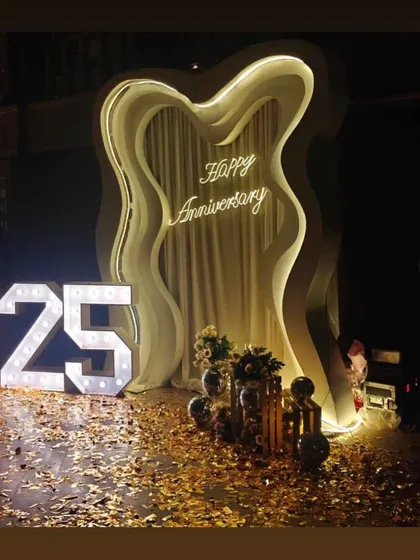 A grand statement for a 25th anniversary. This setup features a custom-lit parametric backdrop, marquee numbers, and gold confetti on the floor to create a truly luxurious and celebratory feel.