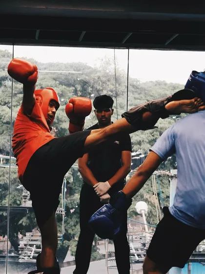 A fighter throws a high kick during a competition, showcasing his skill under pressure.