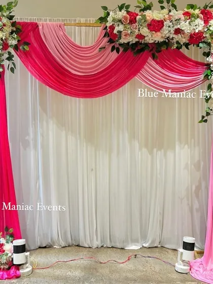 A beautiful stage backdrop with a pink and white theme, featuring a rectangular floral frame and elegant draping.