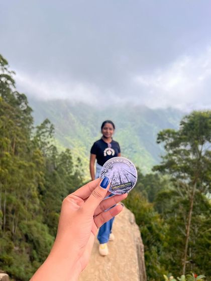 Our Kodaikanal badge held up against the stunning view from Dolphin's Nose.