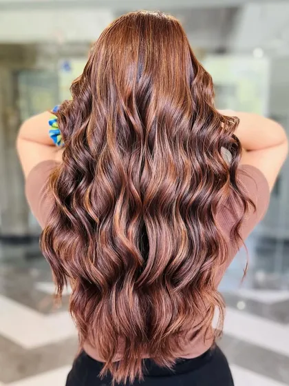 Rich hazelnut hues styled into beautiful, bouncy waves. This look showcases our expertise in creating warm, dimensional brunette colors that are full of life and shine.