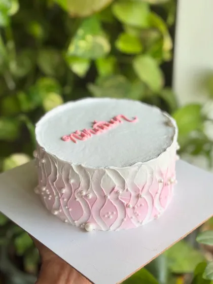 A side view of the "Nineteen" cake, showcasing the beautiful two-tone pink wave piping detail, dotted with pearls for a classy finish.