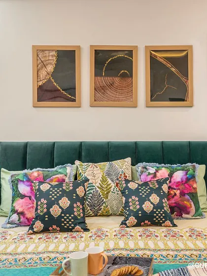 A closer look at the beautiful emerald green bed, styled with a mix of floral and patterned cushions. The bedside features an integrated, back-lit mirror that doubles as a dressing area.