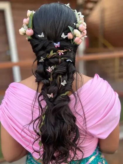 A playful and creative messy braid designed for a Mehendi or Carnival event. This bohemian hairstyle is adorned with a floral crown, delicate butterflies, and interwoven vines, creating a whimsical and unique look.