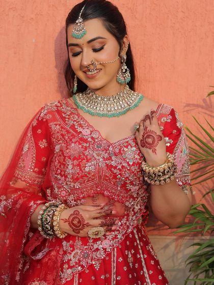A close-up on the bride's happy expression and the beautiful henna on her hands. The blouse details and the turquoise jewelry add a fresh touch to the traditional red.
