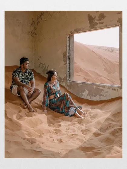 A quiet moment inside an abandoned structure, with sand pouring in through the window. This shot tells a story, with the couple looking out at the desert expanse, creating a cinematic and contemplative pre-wedding portrait.