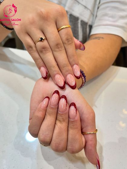A close-up of our red French tip nails, showing the glossy finish and perfect almond shape. This design is both elegant and eye-catching.