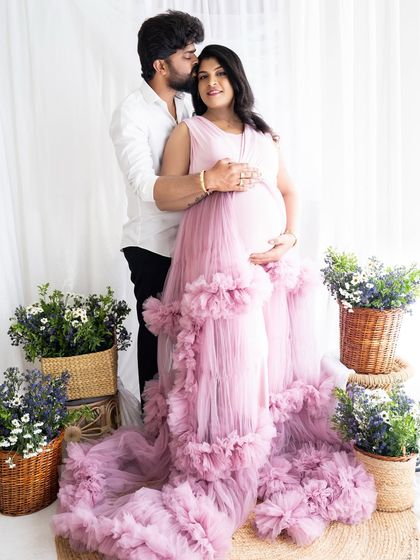 A loving embrace from behind, with the partner kissing the mom-to-be's head as they both hold the baby bump.